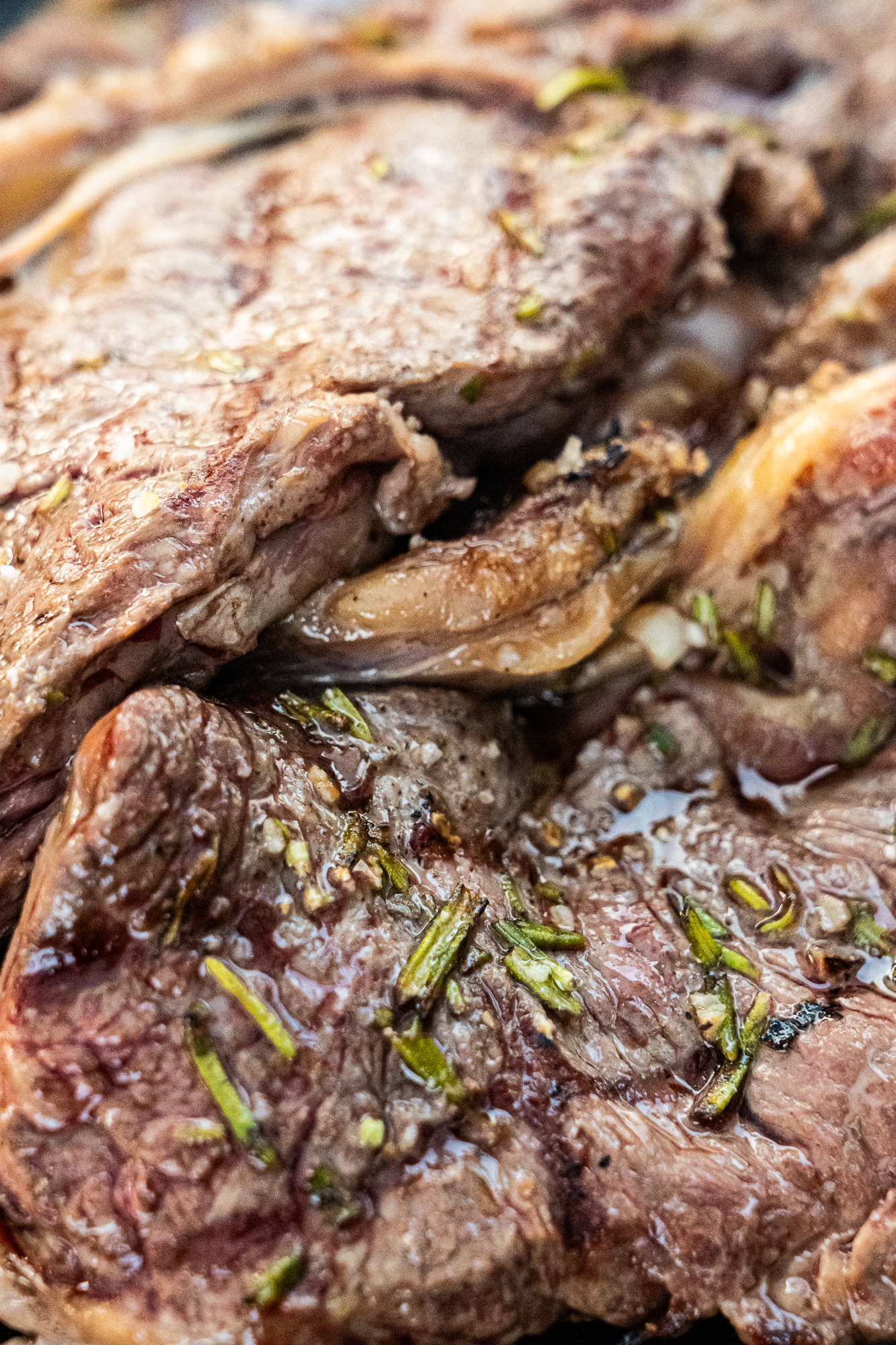 Detalle de carne recién hecha con romero y ajo, aún en la sartén