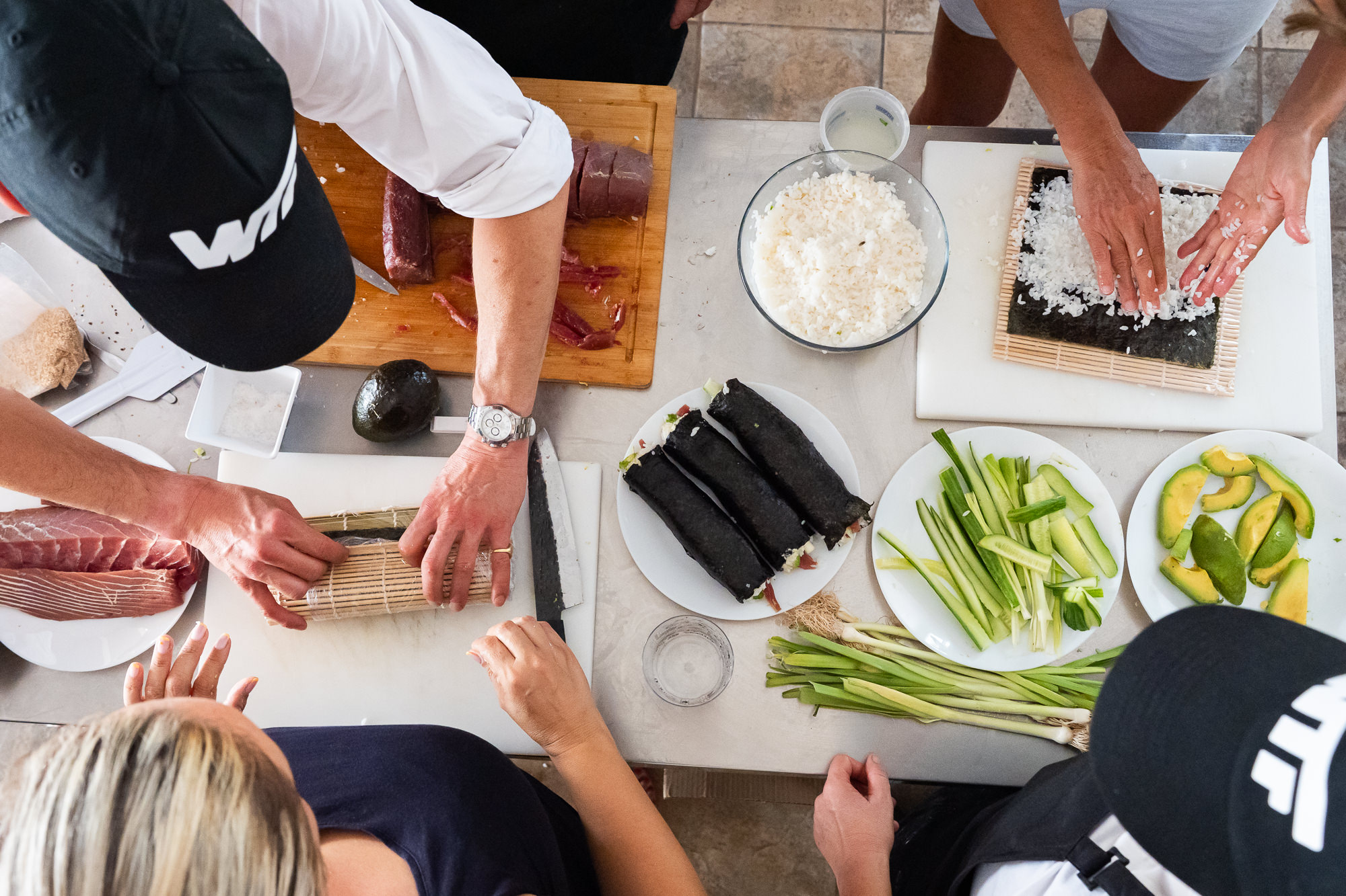 Participantes preparando sushi juntos alrededor de la mesa