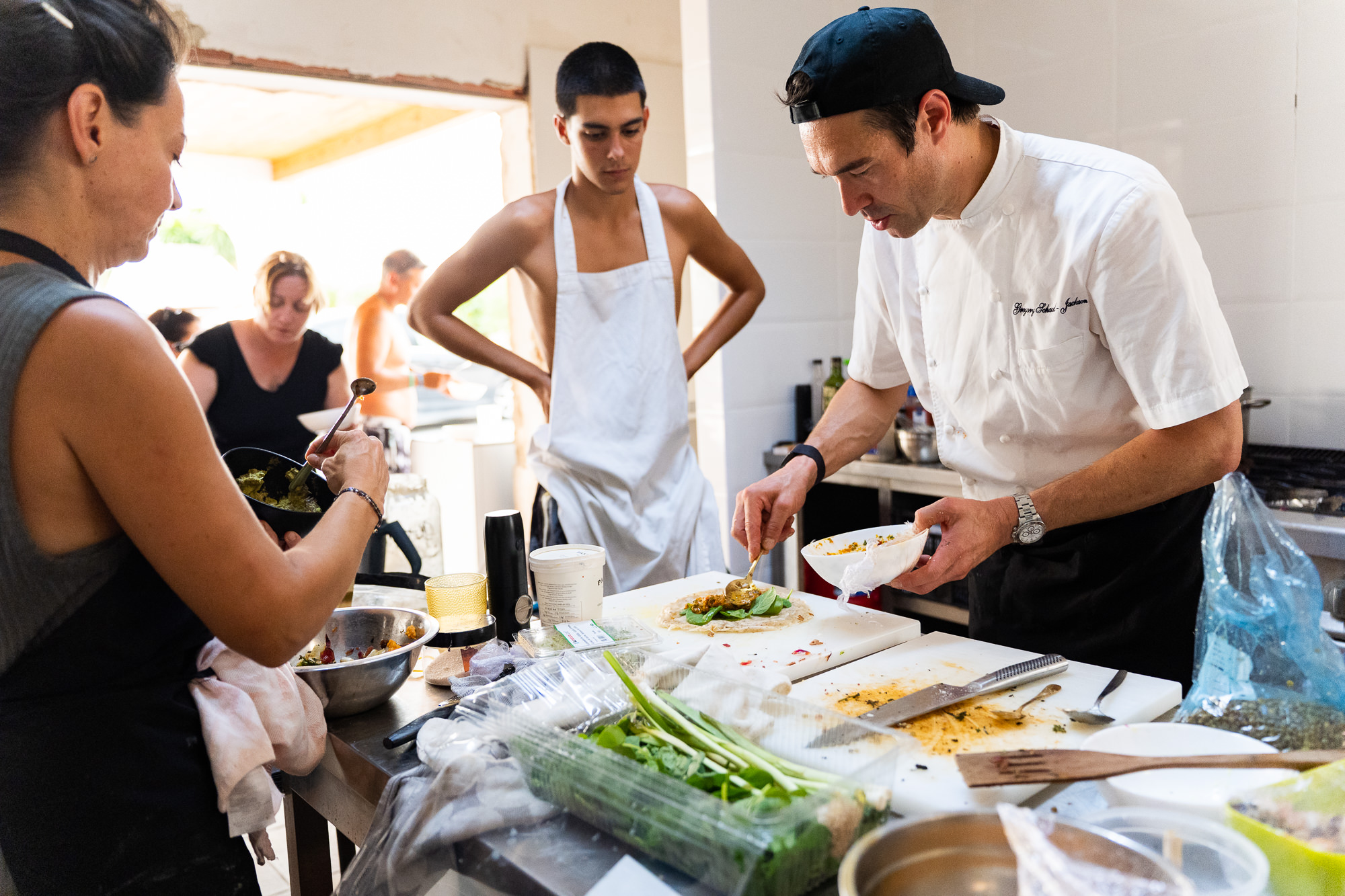 Gregory emplatando mientras los participantes observan en la cocina