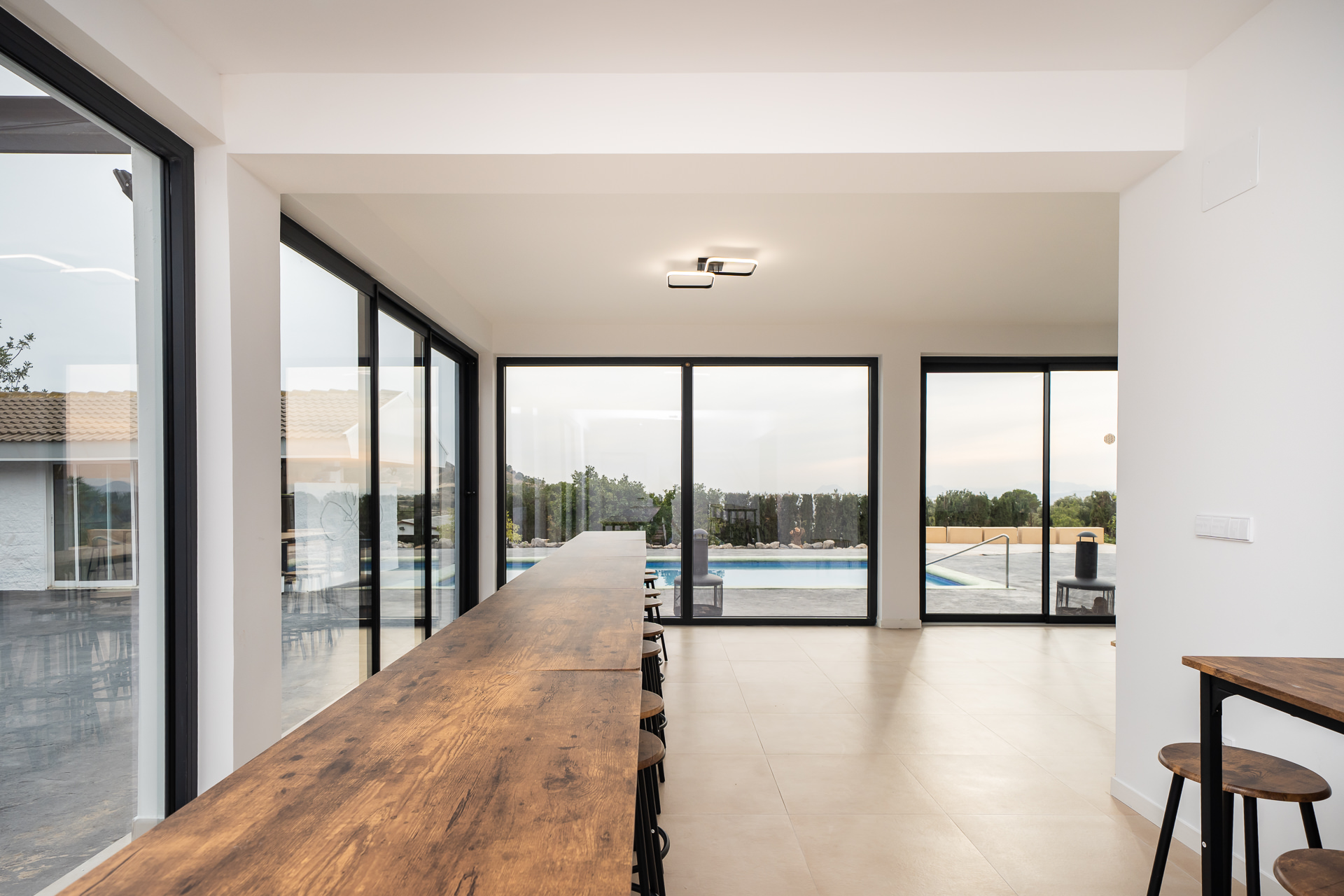 Gran mesa comunal de Villa Amaroo junto a los ventanales y la piscina